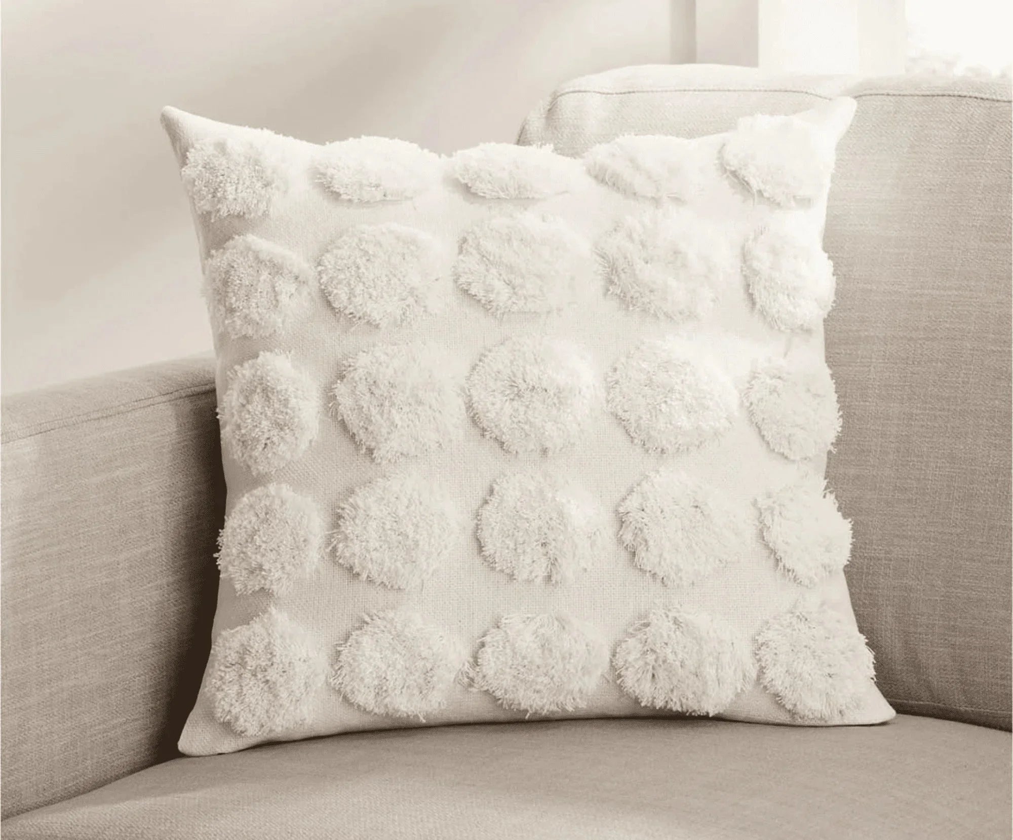 Handcrafted white textured throw pillow with tufted circles on a beige sofa