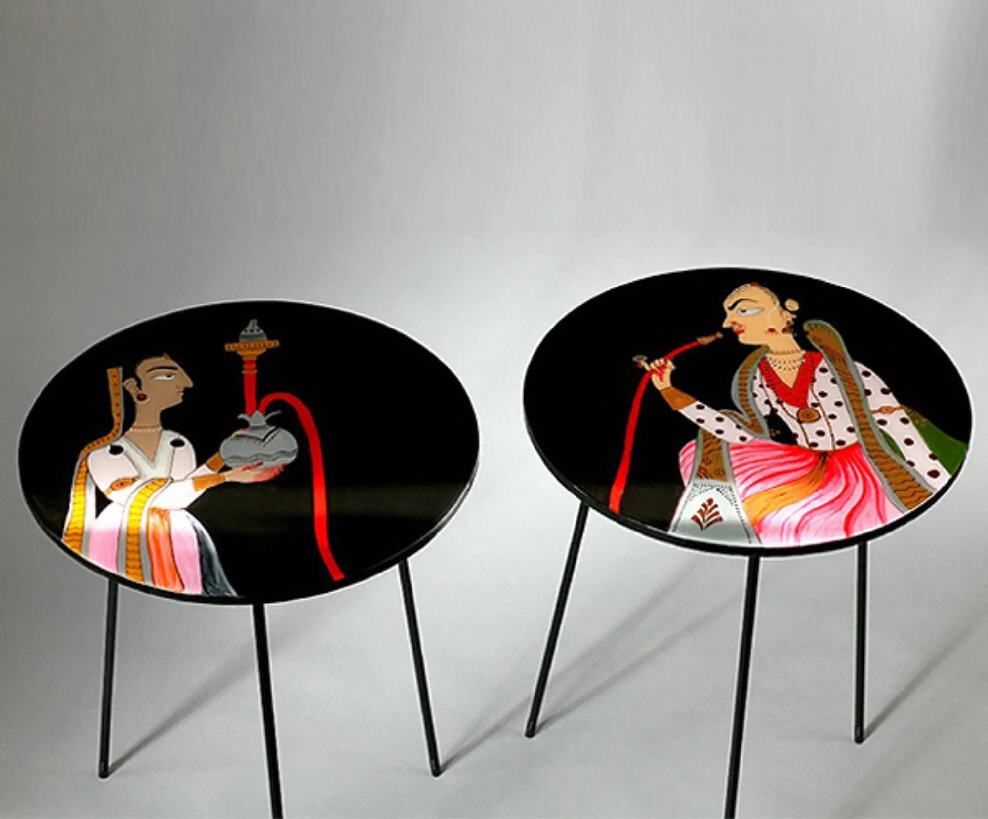 Pair of round accent tables with hand-painted traditional Pakistani art on black tops.