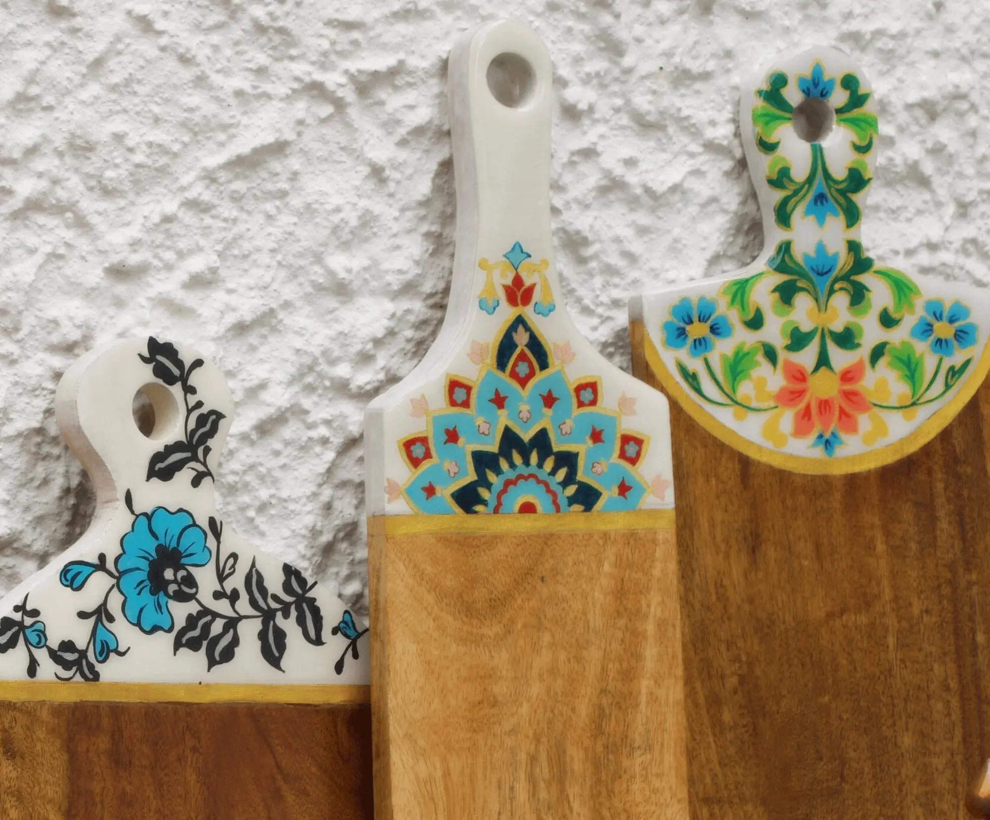 Handcrafted wooden serving boards with colorful floral and geometric patterns on handles